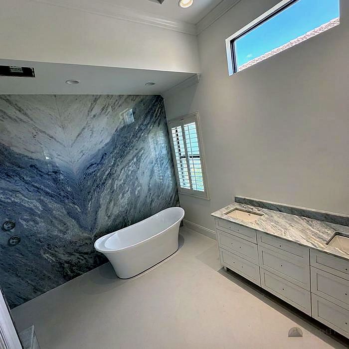 Freestanding tub against a stone feature wall